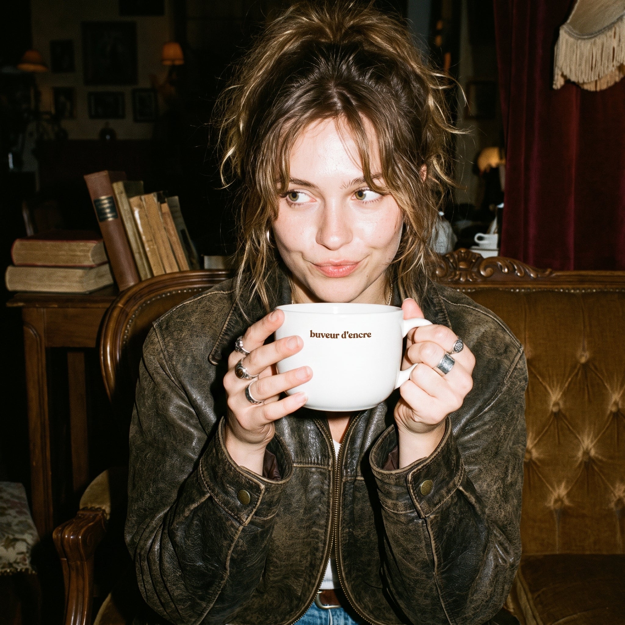Woman holding a white mug with text in a cozy room.