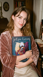 Woman holding a book titled 'Epic Love' in a cozy indoor setting